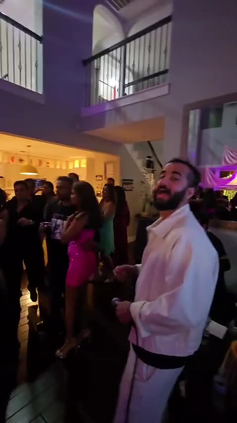 Wandering Roots vocalist in white performing in front of a packed dance floor under purple lights
